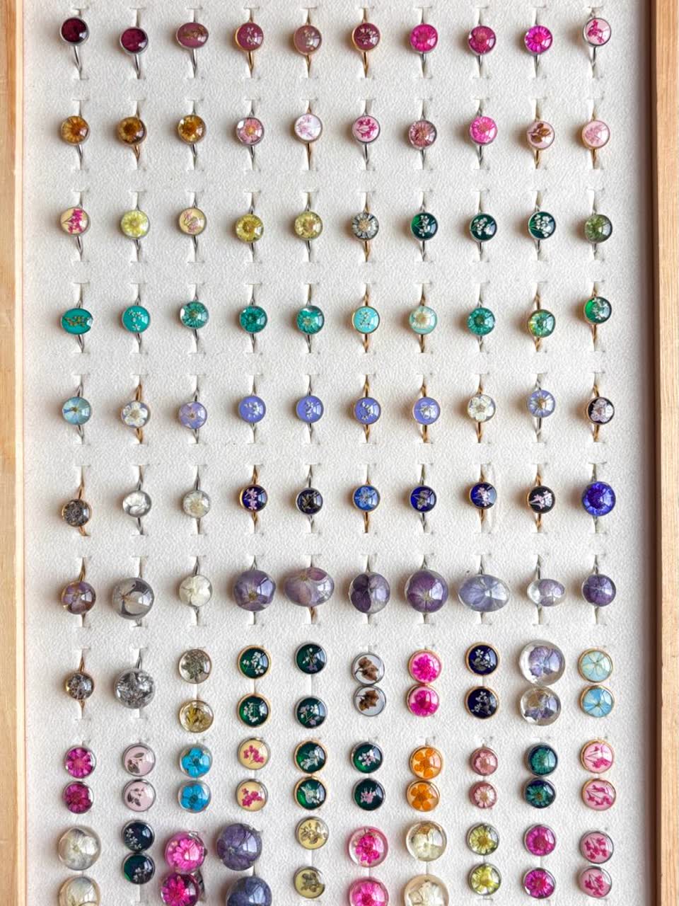 Contoh aneka cincin dan anting bunga berwarna-warni dalam kotak pajangan